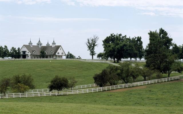 White fences below a barn with three cupolas